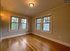 Inviting apartment corner with elegant wood flooring and large windows offering natural light and lush greenery views.