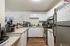 Modern kitchen with sleek stainless steel appliances, ample white cabinetry, and elegant counter space.