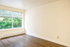 Bright and inviting room with elegant hardwood floors and a large window drenching the space in natural light.