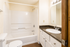 Elegant bathroom featuring a modern bathtub, sleek vanity with dark countertop, and bright lighting.