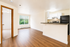 Bright and inviting open-concept living area with modern kitchen, featuring sleek appliances and beautiful wood flooring.