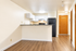 Contemporary kitchen with sleek white cabinets, black appliances, and elegant wooden flooring, perfect for modern living.