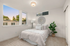 Bright and airy bedroom with modern decor, featuring a cozy bed, stylish lamp, and large windows showcasing a serene outside view at sunset.