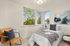 Bright and inviting bedroom with large windows, modern decor, and a cozy reading nook, offering serene natural views.