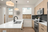 Sleek modern kitchen with glossy countertops, elegant cabinetry, and stainless steel appliances under stylish pendant lights.