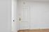 Inviting entryway with elegant white door and golden handle, complemented by sleek hardwood flooring.