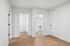Welcoming hallway featuring natural wood flooring leading to a chic bathroom with gold fixtures and crisp white decor.