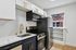 Modern kitchen featuring sleek stainless steel appliances, elegant white cabinetry with gold accents, and a stylish marble countertop.