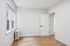 Bright and inviting room with large windows, sleek hardwood floors, and a classic white door, perfect for creating a cozy and stylish living space.
