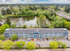 Aerial view of a charming apartment complex nestled beside a tranquil lake, surrounded by lush greenery and serene residential area.