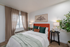 Bright and cozy bedroom featuring a bold orange headboard, elegant decor, and ample natural light from large windows.