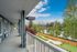 Charming apartment view with a serene riverside setting, lush greenery, and a spacious balcony walkway offering tranquil living.