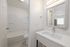 Bright modern bathroom featuring a sleek vanity with an illuminated mirror and a pristine bathtub.
