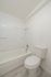 Bright bathroom featuring a pristine bathtub, efficient showerhead, and modern toilet, creating a sleek and clean ambiance.