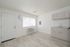 Bright, modern apartment interior with sleek laminate flooring, compact kitchen area, and large window providing ample natural light.