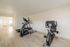 Bright home gym with sleek elliptical and stationary bike on light wood flooring, perfect for fitness enthusiasts.
