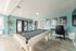 Bright and inviting game room with a classic pool table, modern teal walls, and elegant decor, perfect for relaxation and entertainment.