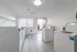 Bright and modern laundry room in an apartment building, featuring multiple white washing machines, large window, and sleek wooden flooring.