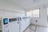 Bright and modern laundry room with multiple high-efficiency washers and dryers, ample natural light, and sleek shelving for convenience.
