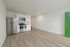 Modern kitchen with stainless steel appliances, sleek white cabinetry, and light wood flooring features an open layout and vibrant green door.