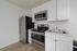 Modern kitchen with sleek stainless steel appliances, minimalist white cabinetry, and elegant wooden flooring.