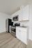 Modern kitchen with sleek stainless steel appliances, elegant white cabinetry, and light wood flooring.