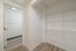 Spacious walk-in closet with modern shelving and sleek hardwood flooring, perfect for organized living.