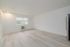 Bright and airy living space with modern wood flooring and large window, featuring a sleek air conditioning unit.
