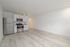 Modern apartment with sleek stainless steel appliances and elegant light wood flooring in a spacious open-plan kitchen and living area.