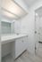 Bright and modern bathroom with sleek white cabinetry and elegant countertop in a contemporary apartment setting.