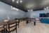 Modern entertainment room featuring a foosball table, shuffleboard, sleek gray walls, vibrant art, and a cozy seating area with a large flat-screen TV.