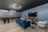 Spacious and stylish multipurpose room with modern furniture, foosball table, and large wall-mounted TV, ideal for entertainment and relaxation.