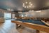 Luxurious apartment recreation room with elegant billiards table, modern seating, and ambient lighting.