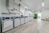 Bright and spacious laundry room with multiple washing machines, sleek piping, and modern lighting.