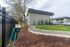 Welcoming apartment exterior with lush green lawn, paved pathway, and convenient pet station near parking area.