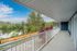 Scenic apartment balcony with serene lake view and lush greenery, perfect for relaxation.