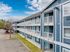 Charming blue apartment complex with three levels of inviting balconies and vibrant doors, set against a bright blue sky.