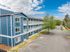 Modern blue apartment building with white accents featuring spacious balconies, ample parking space, and lush greenery in a serene neighborhood setting.