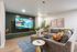 Cozy and modern living room with a large wall-mounted TV, comfy gray sectional sofa, vibrant cushions, stylish coffee tables, and elegant wall art, perfect for relaxation.