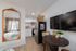 Cozy urban apartment featuring a stylish kitchen with modern appliances, inviting dining area, and elegant decorative mirror reflecting abundant natural light.