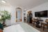 Charming studio apartment with a sleek kitchen, cozy dining area, and elegant decor. Features a large mirror, vibrant plant, and modern accents.