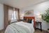 Bright and cozy bedroom featuring a vibrant orange headboard, elegant wall art, and lush greenery creating a serene atmosphere.
