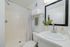 Contemporary bathroom with elegant fixtures, a framed mirror, and fresh greenery provides a tranquil spa-like ambiance.