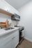 Modern kitchen space with sleek white cabinetry, stainless steel appliances, and elegant wooden accents.