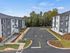 Modern apartment complex with ample parking, surrounded by lush greenery and vibrant landscaping, offering a peaceful living experience.