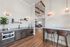 Elegant open-concept kitchen with sleek cabinetry, modern bar seating, and cozy living space featuring high ceilings and contemporary lighting.