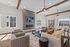 Modern living room with stylish gray furniture, large windows, and a sleek wall-mounted TV, offering abundant natural light and cozy ambiance.