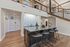 Contemporary apartment interior featuring a chic kitchen island with elegant bar stools, stylish backsplash, and an inviting staircase leading to an upper level.