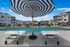 Luxurious apartment community featuring a sparkling pool, stylish poolside seating, and modern architecture under a clear blue sky.