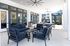 Spacious modern patio with stylish dark blue seating, sleek ceiling fans, and elegant glass doors, offering a perfect blend of indoor-outdoor living.